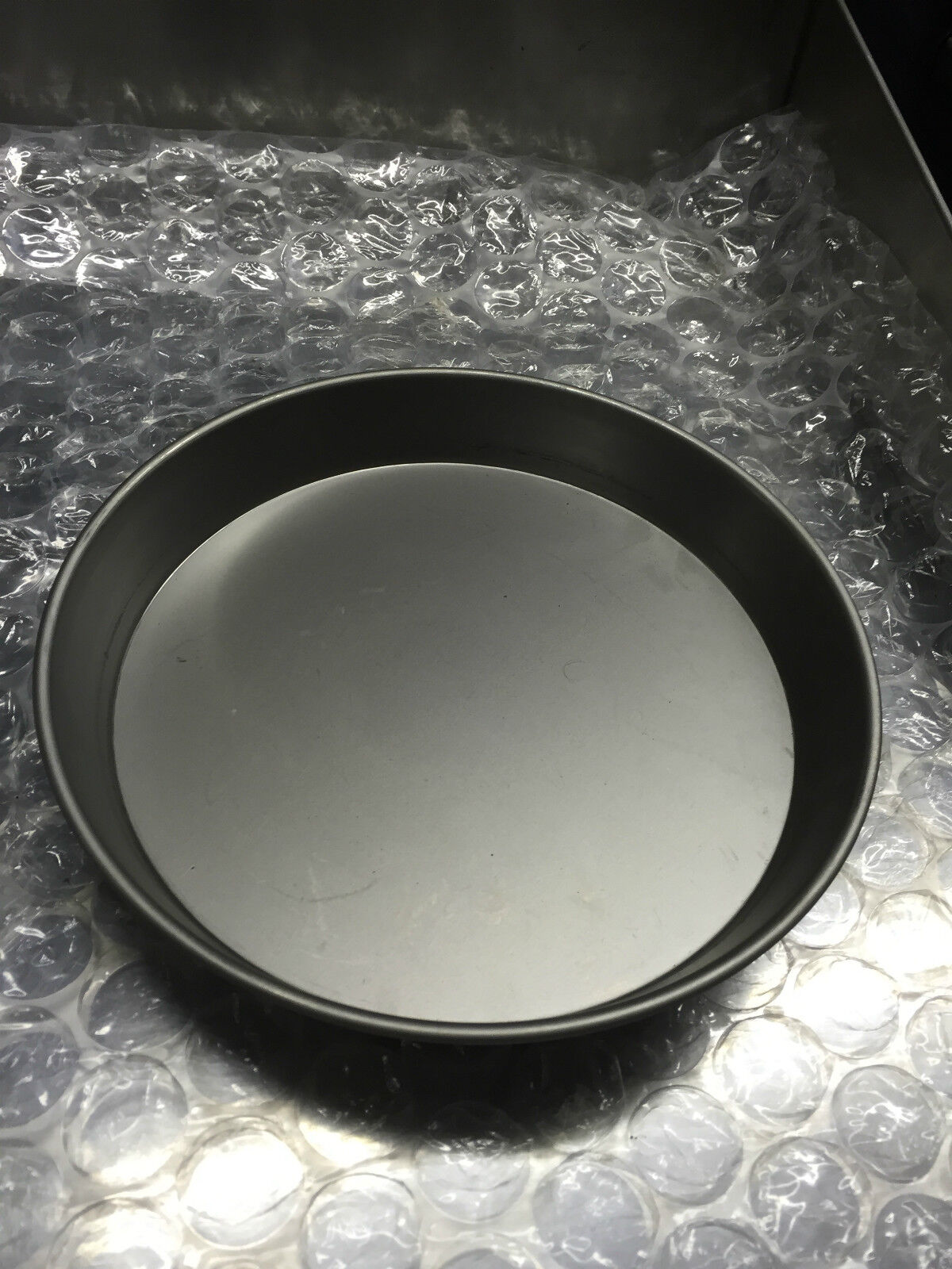 Close-up of the Iron Pizza Pans Set of 10, showcasing the high-quality black iron construction ideal for cooking delicious deep pan pizzas.