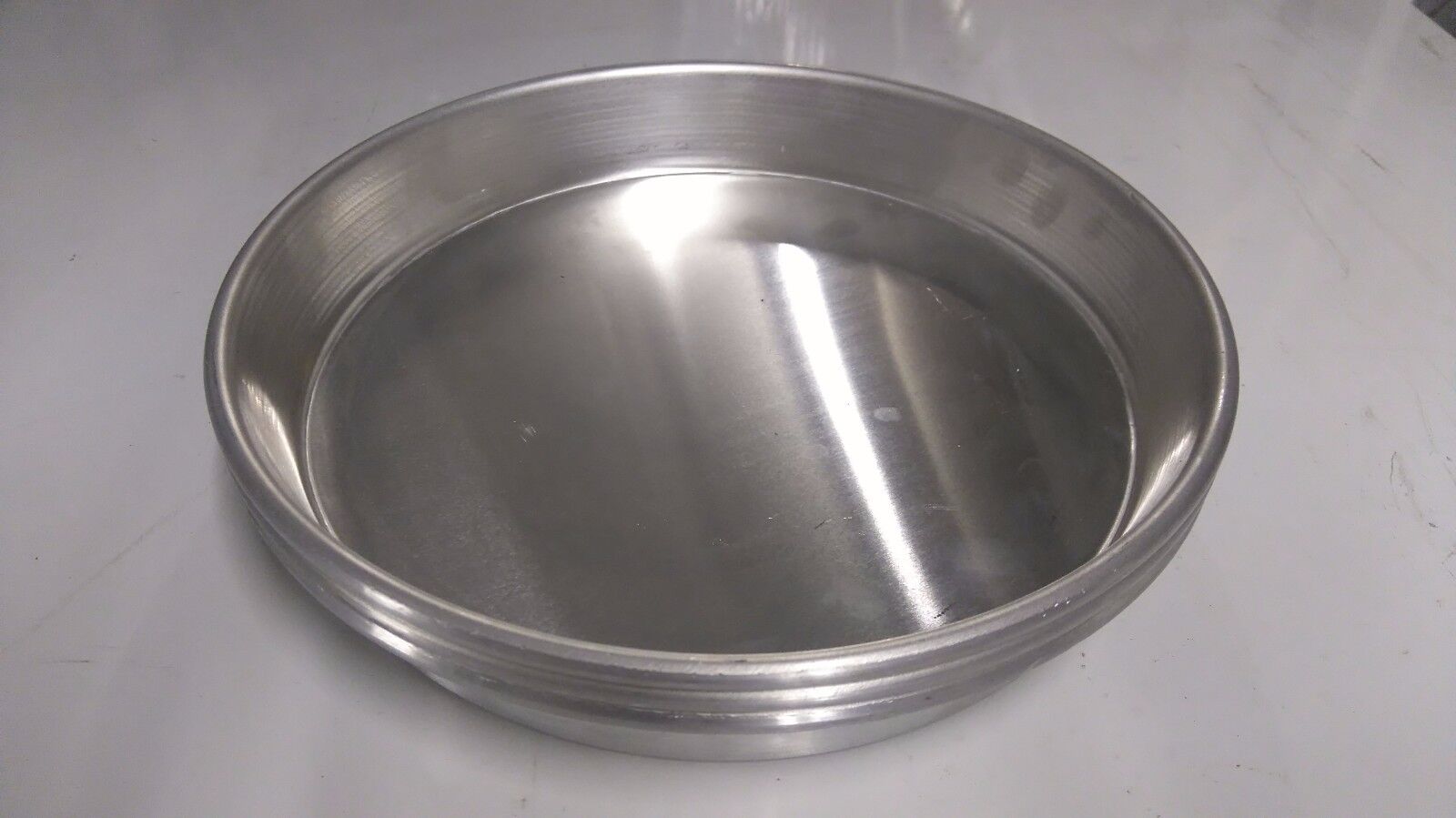 Aluminium pizza pans set displayed with fresh deep pan pizza, emphasizing the ease of release and cooking quality.